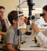 Young child receiving a comprehensive eye exam with a concerned parent watching nearby at an Illinois optometry office