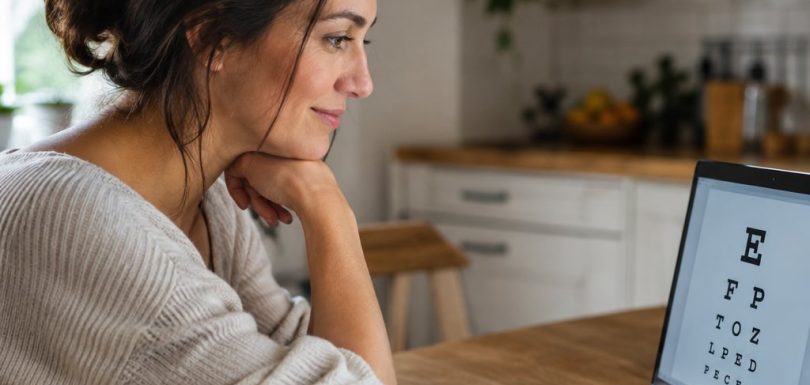 Woman taking an online vision test on a laptop at her kitchen table